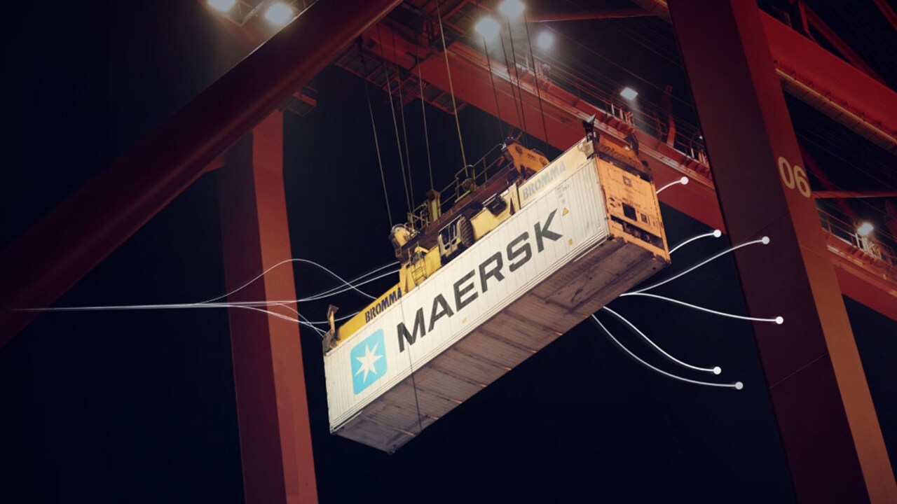 Container being lifted by a crane at night.