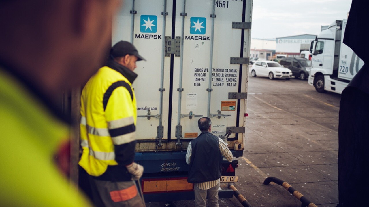 Workers inspect a Maersk container.