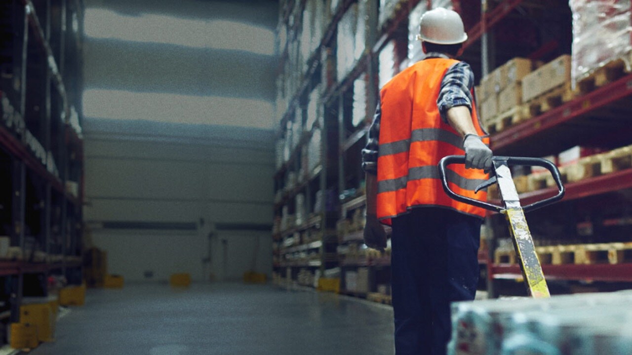 Person carrying packed boxes in warehouse.