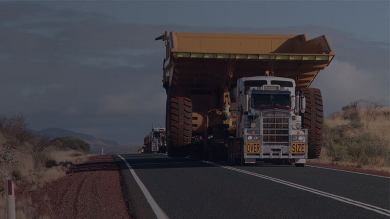 Mining Logistics services – An open flatbed truck of Maersk carrying the mining machinery in Africa.