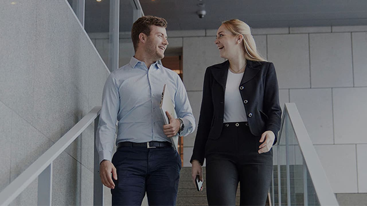 Maersk Management Consulting (MMC) – Two smiling employees discussing business at the Maersk corporate office.