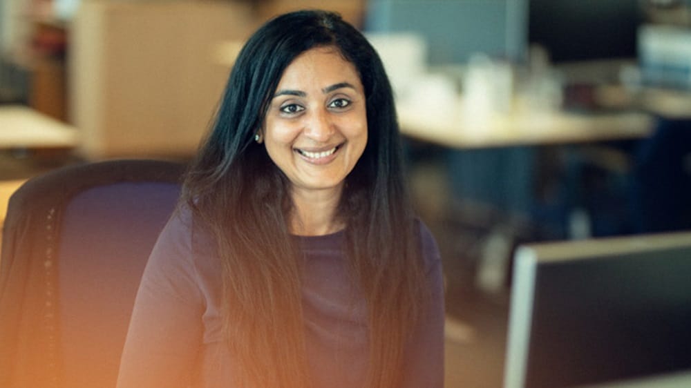 A smiling female data employee seated at her workstation in an office.