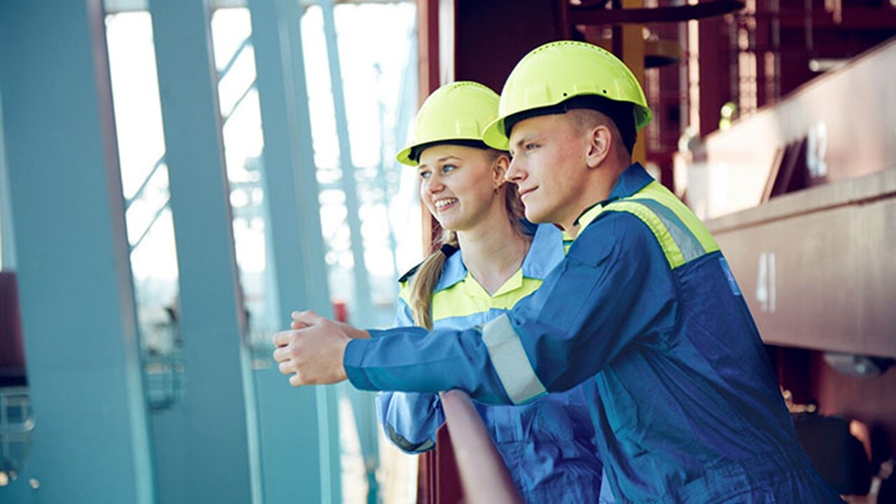 Cadets in boiler suits looking over the side of a container ship From Cadet Administration and Recruitment Denmark