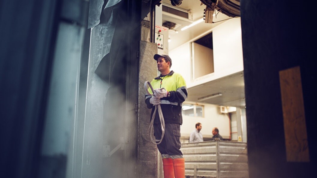 Man with dark hat in yellow vest and orange boots