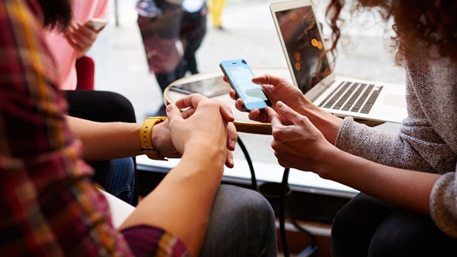 Two people sitting by a table while looking on a phone