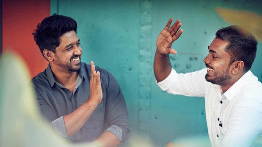 Two men of Indian origin high-fiving and smiling