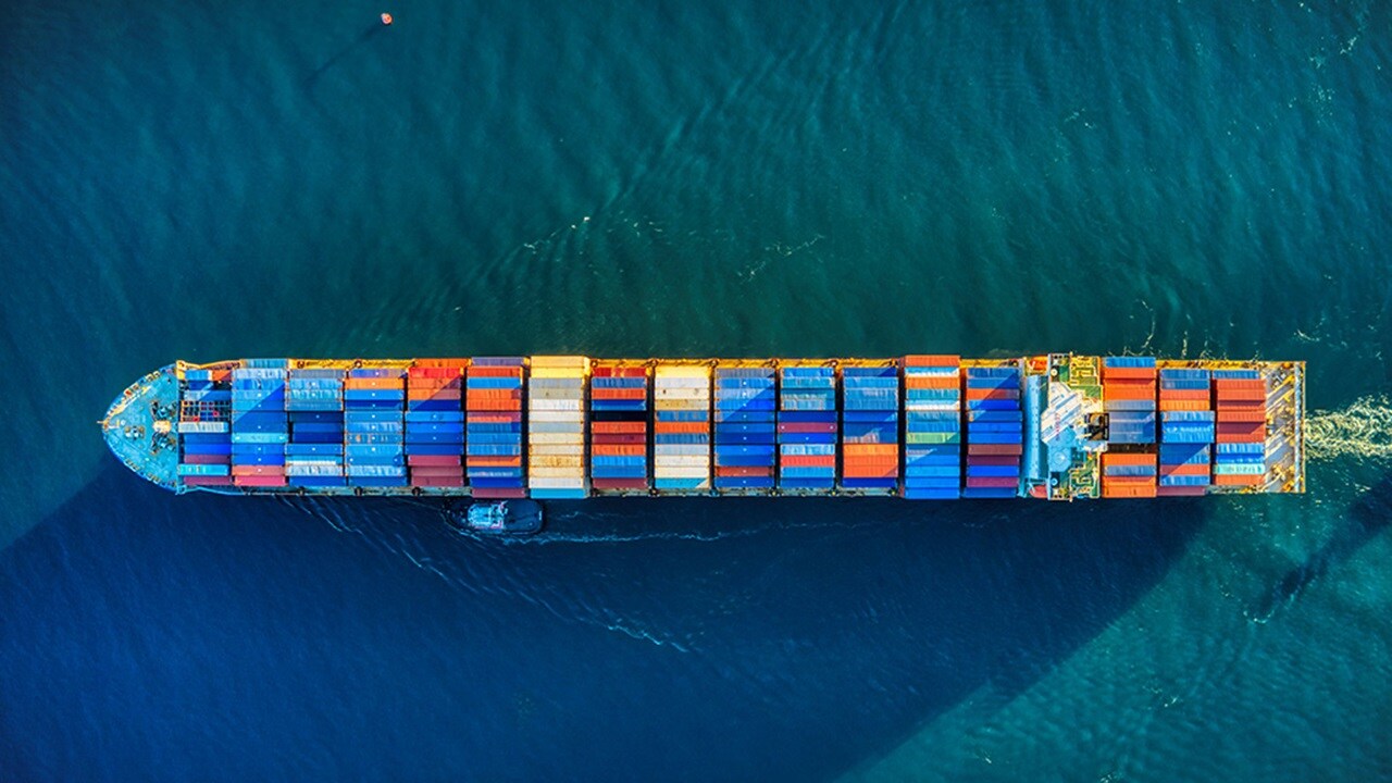 A cargo ship loaded with multicoloured containers is seen from above.