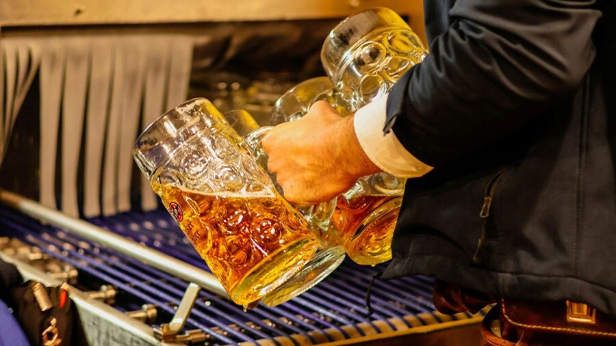 Person holding steins of beer at Oktoberfest.