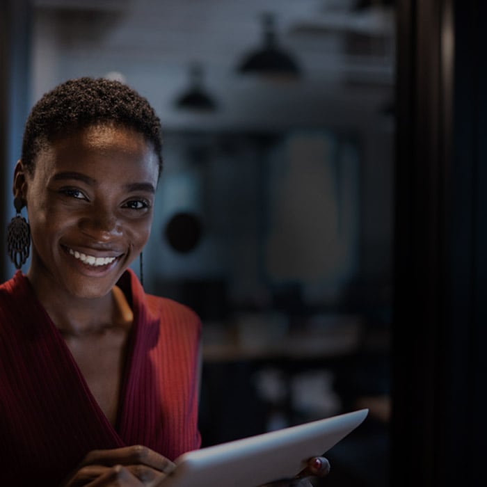 smiling black woman with red vest holding a tablet
