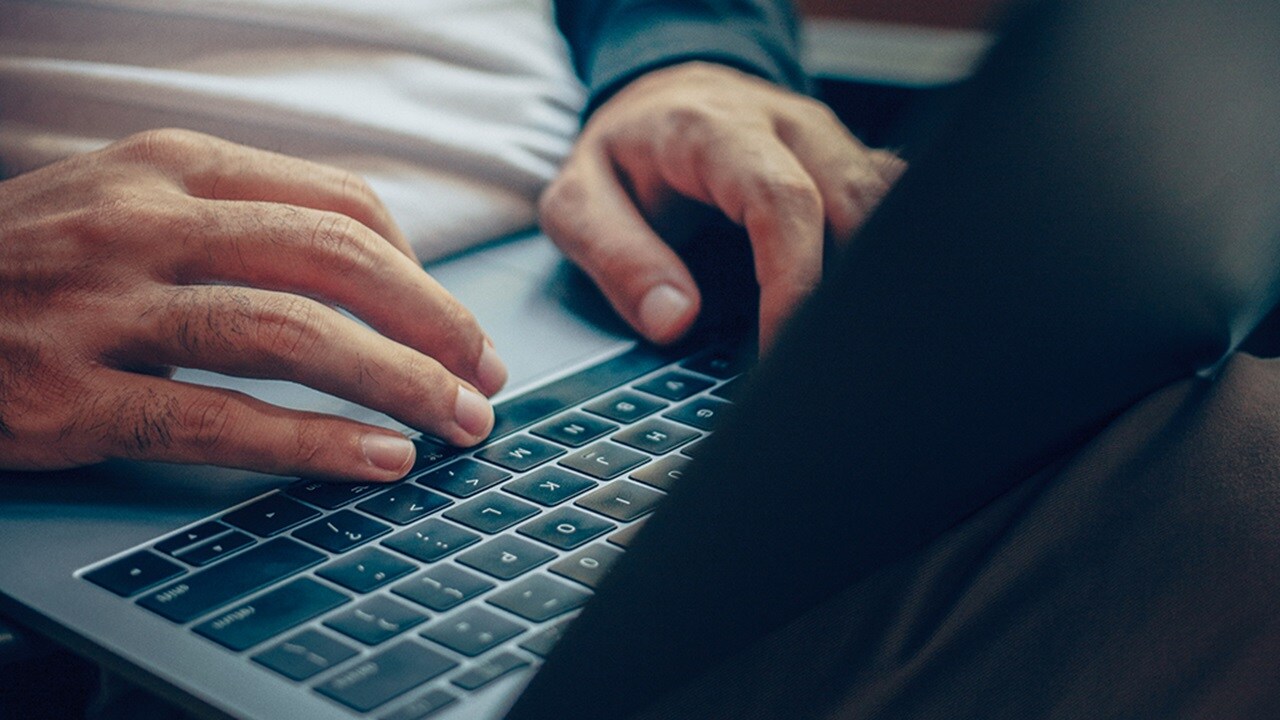 Human hands typing on a laptop keyboard