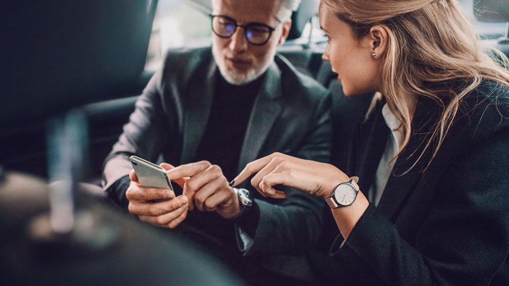 A man and a woman sit side by side in a taxi. 