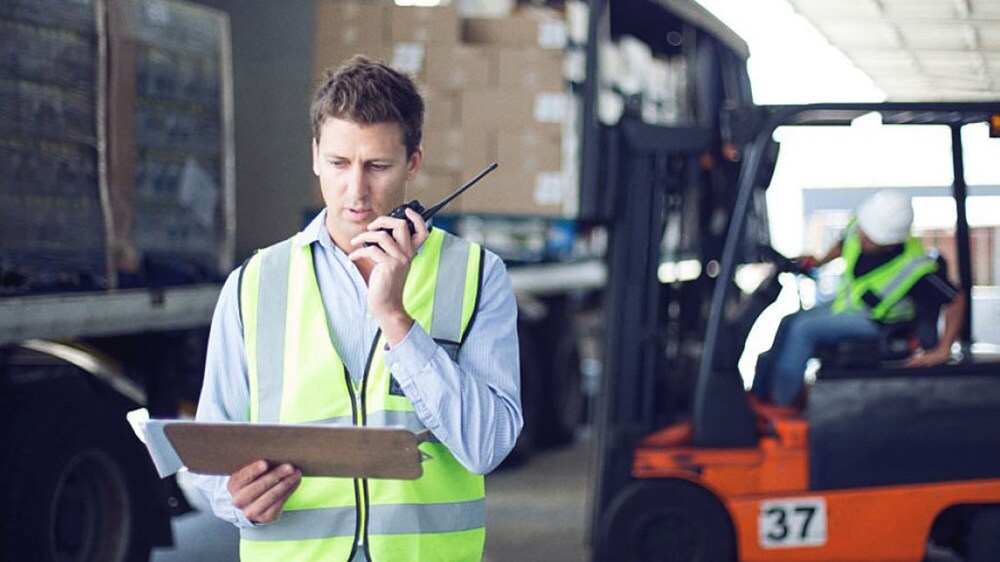 Two workers in high-visibility vests handling cardboard boxes in a warehouse.
