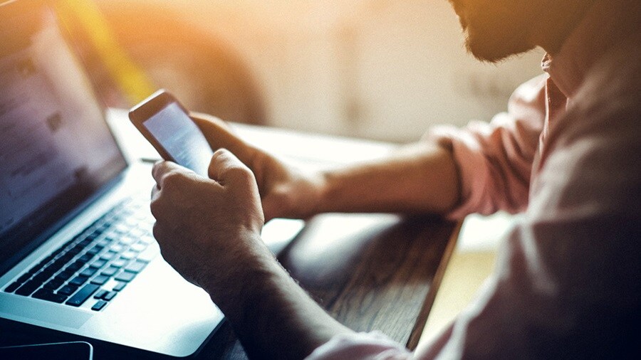 A person multitasking with a laptop and smartphone, and processing a return on their purchase. 