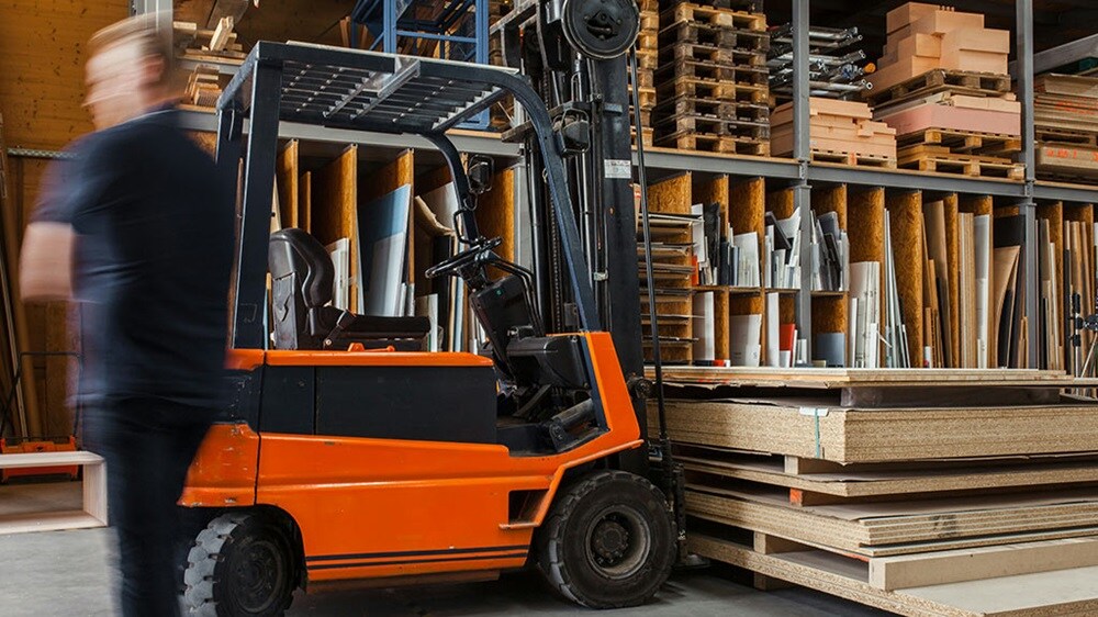 A man with a forklift in a warehouse doing inventory