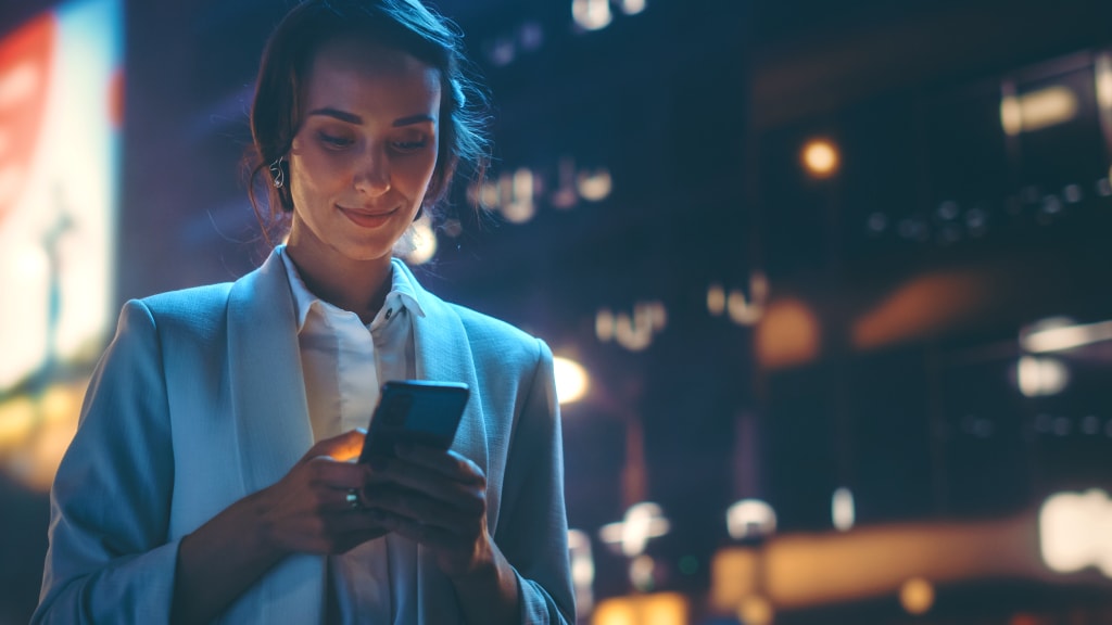 A smiling woman holding a digital device and explaining to a group of people