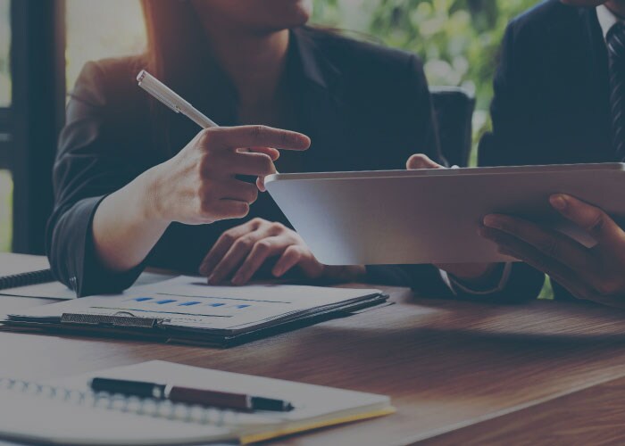 Two sets of hands working on a tablet