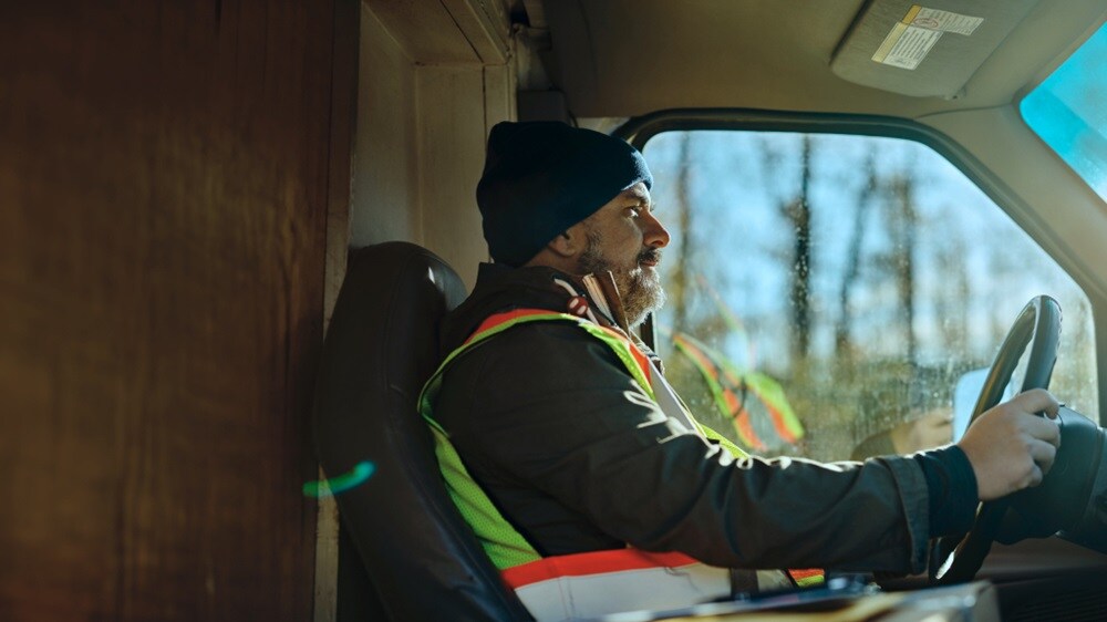 Close-up of a man behind the steering wheel in a truck carrying inland cargo.
