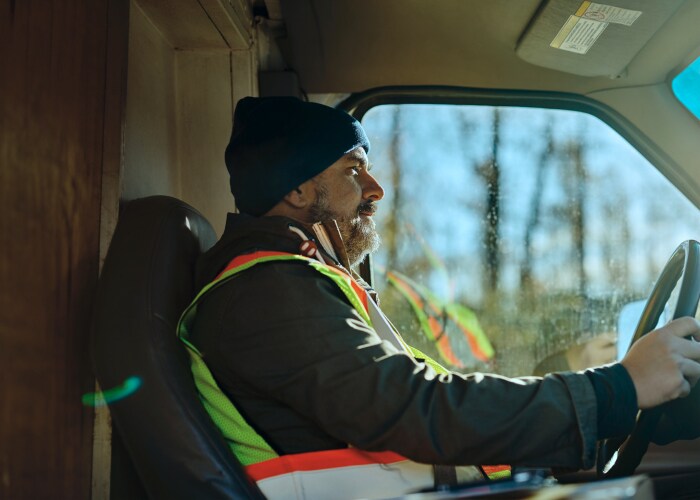 Close-up of a man behind the steering wheel in a truck carrying inland cargo.