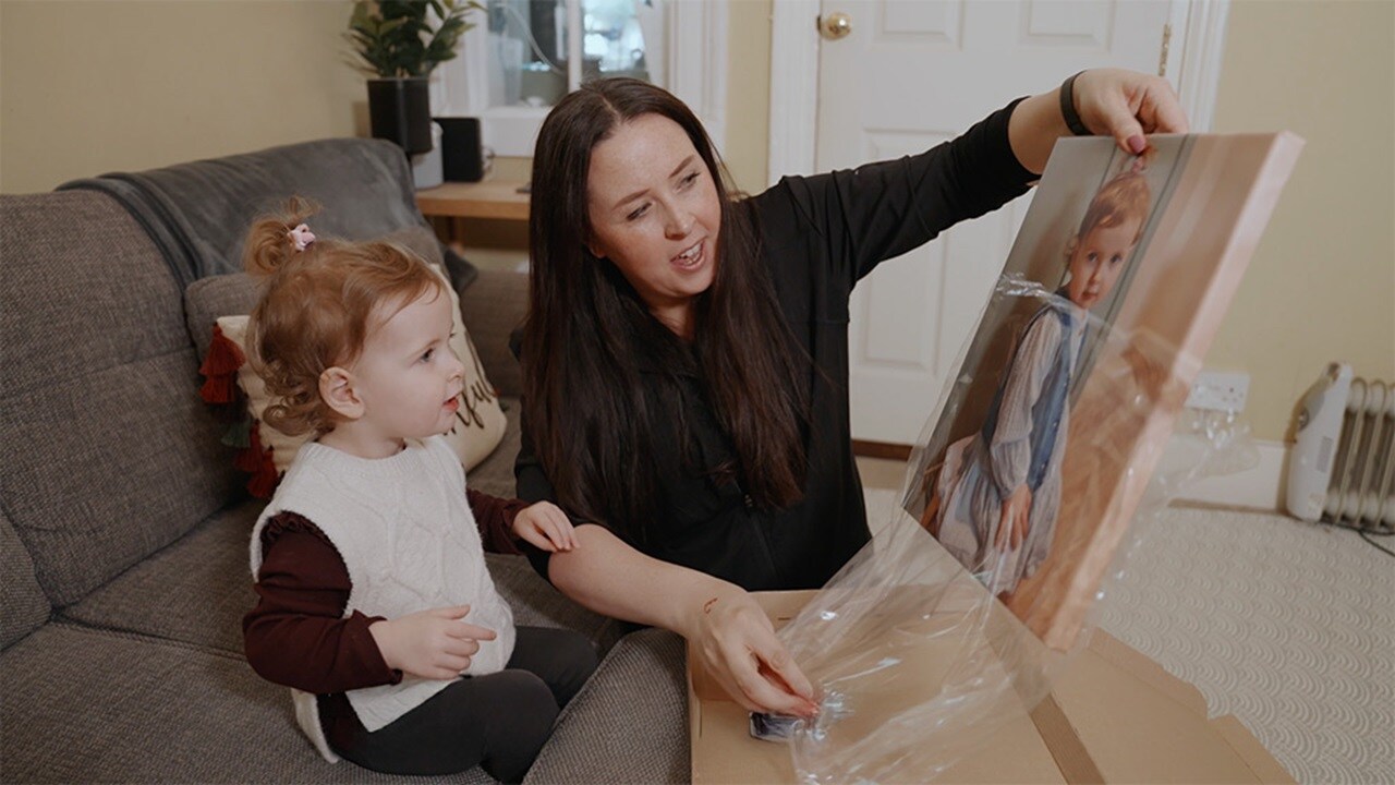 A woman and a child smiling at a framed picture.
