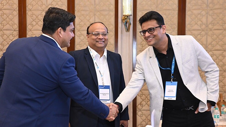 Three men engaged in a handshake at a conference table, representing partnership and mutual understanding.