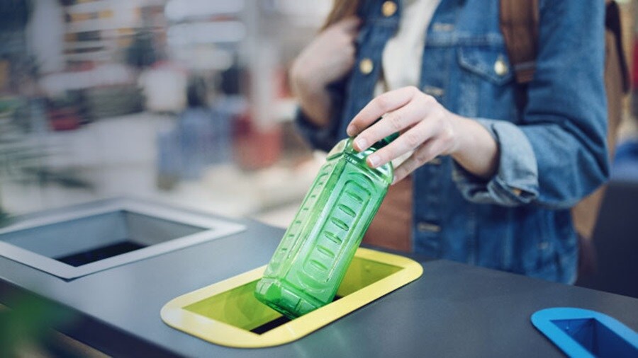 female throwing an empty bottle in trash