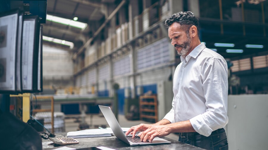 A man working on his laptop inside a warehouse