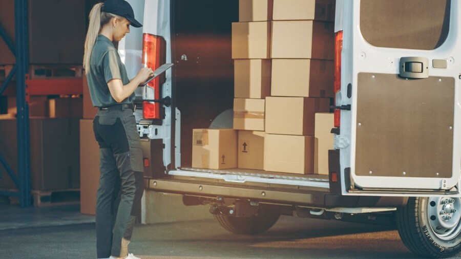 Female delivery executive standing next to a delivery van