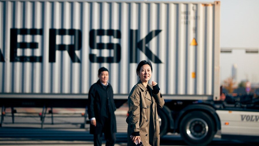 Two people in front of a Maersk container connecting Asia and Europe through the Middle Corridor.
