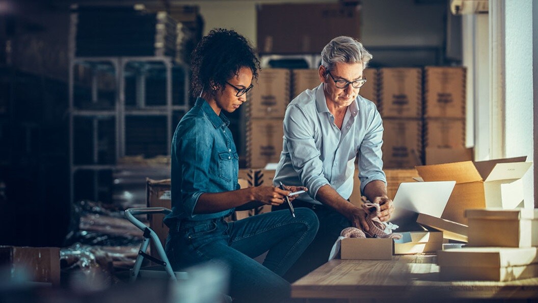 two people stand next to a desk examining