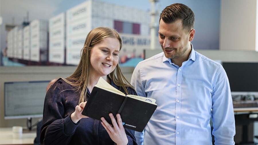 Maersk Customs Services consultants looking at customs clearance process in a notebook.