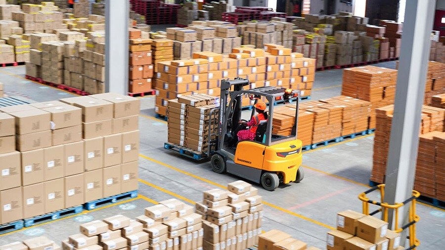 Woman driving a forklift in an ecommerce fulfilment warehouse.