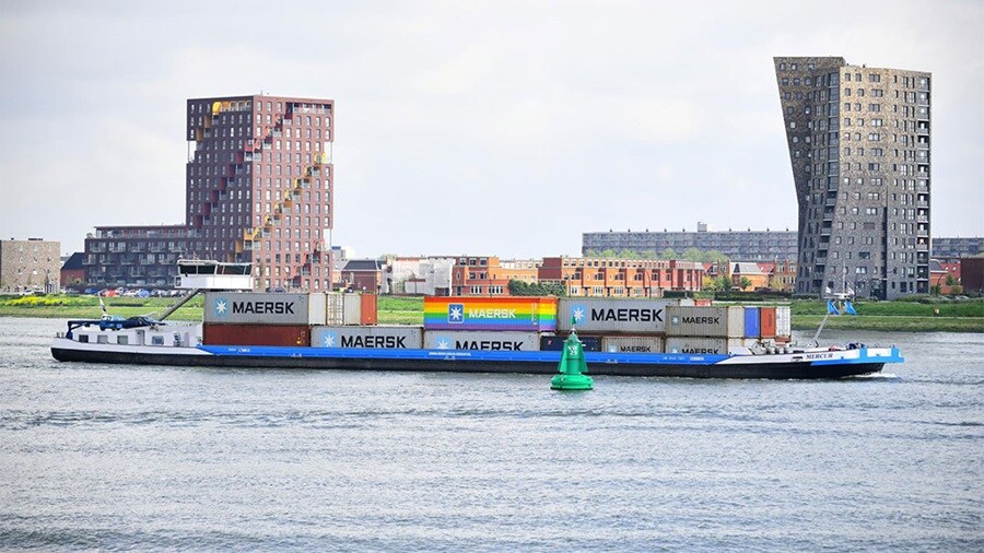 Barge with Maersk containers sailing on a river.