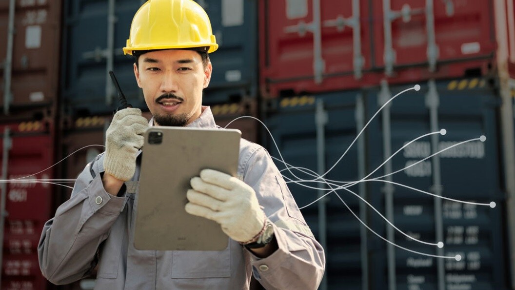 A construction worker in a hard hat is using a tablet computer to review plans or data on-site.
