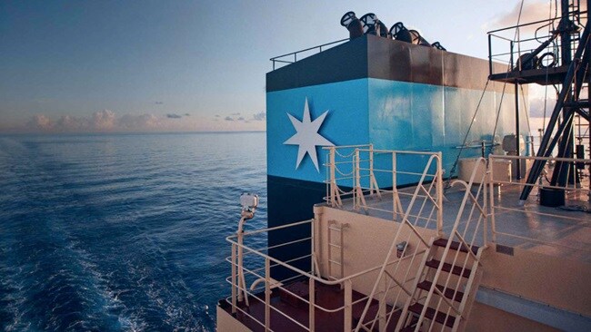A large ship in blue and white colors, prominently displaying a star, sailing on calm waters.