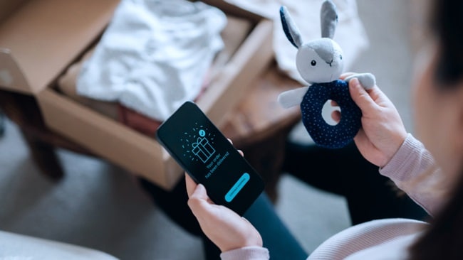 A woman holds a stuffed animal in one hand while using a smartphone with the other hand.