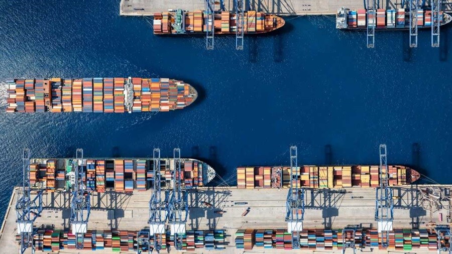 Aerial view of container ships docked at a busy cargo port terminal.