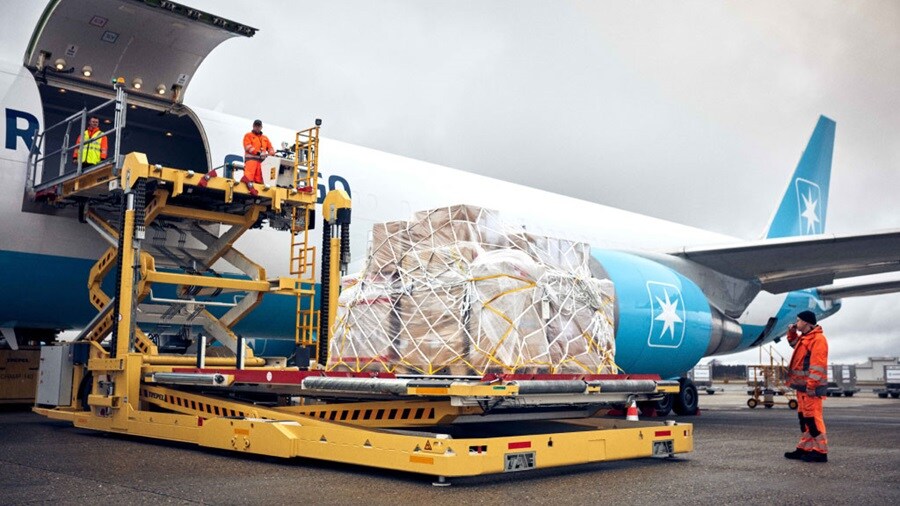 Maersk cargo being loaded onto aircraft by ground crew.