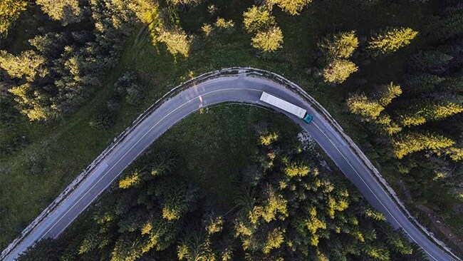 Truck driving on a winding forest road.