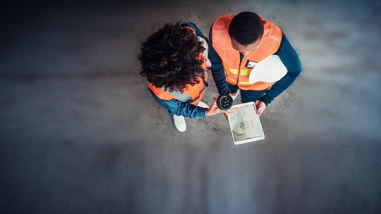Two individuals in safety vests reviewing a document together, focused on the information presented on the paper.