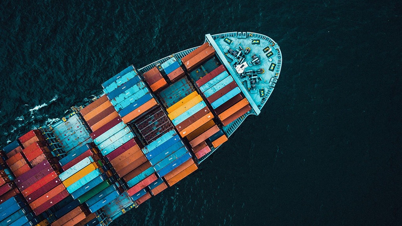 Aerial view of a large container ship navigating through the deep blue ocean waters.