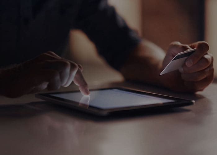 Close-up of a person’s hand making online payment using their credit card on their tablet. 