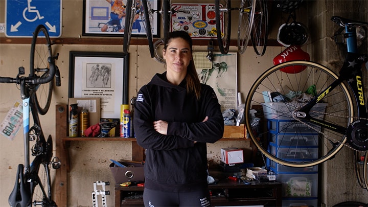 Mandy Marquardt, ciclista de sprint, com equipamento de ciclismo ao fundo.