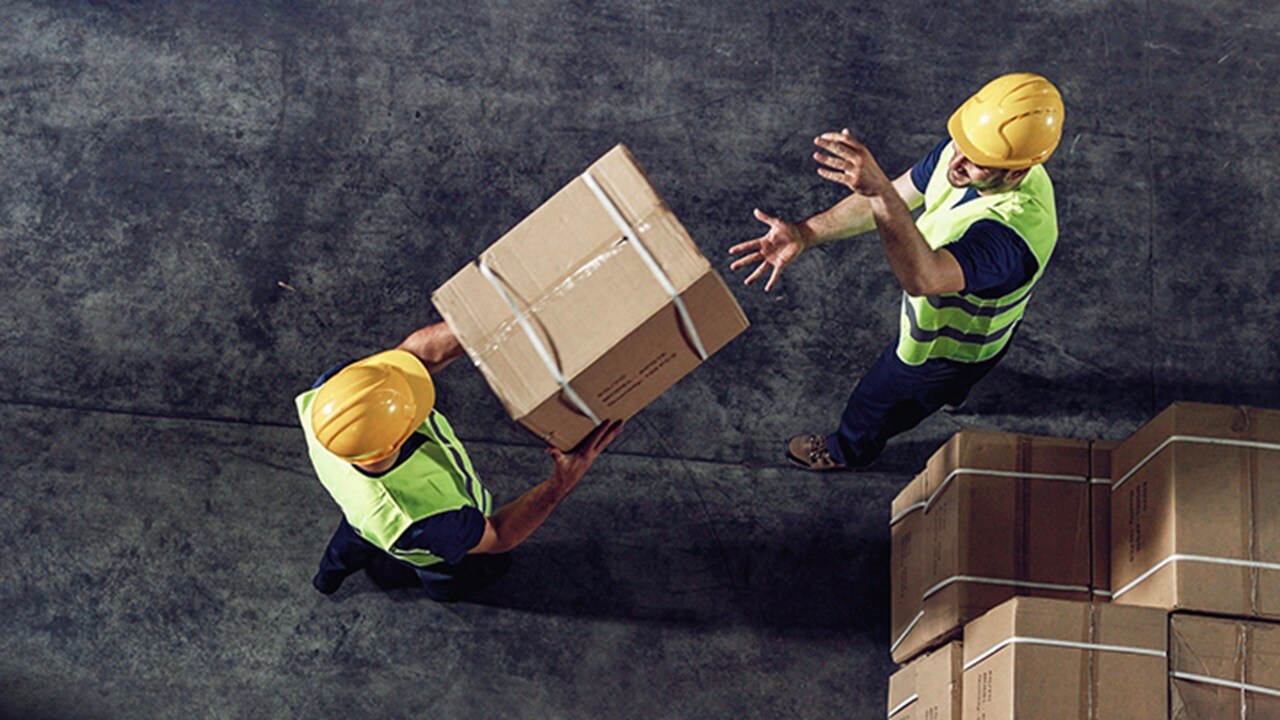 Two male workers moving cargo boxes in a depot.