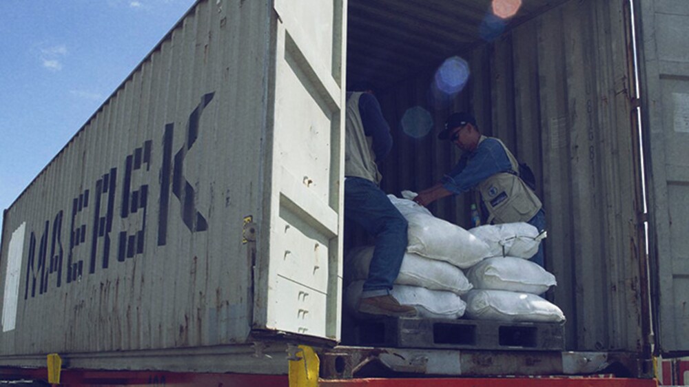 Aid and relief logistics – A couple of workers handling cargo in a Maersk container.