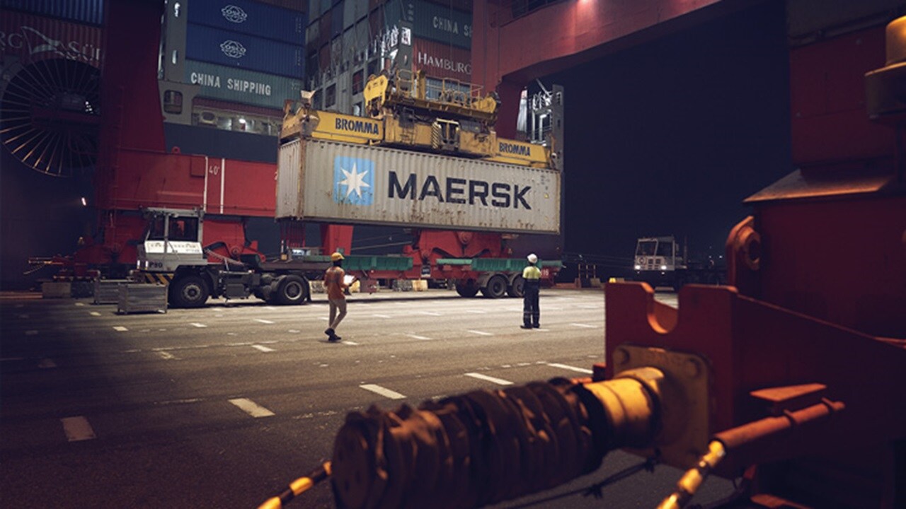 A Maersk terminal with workers and a cargo container being lifted.