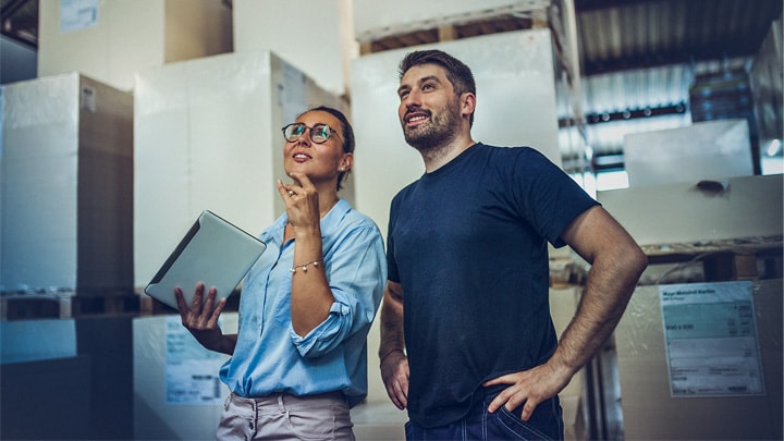 A smiling man and woman looking at cargo boxes in a warehouse.