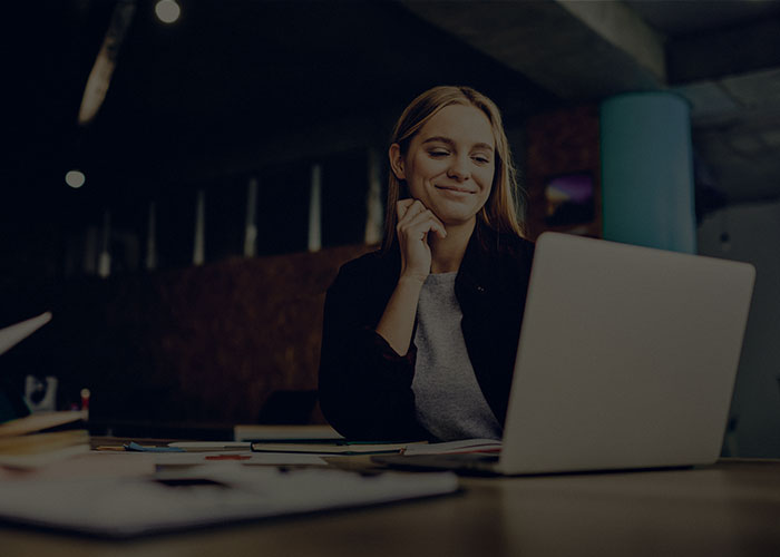 A smiling young woman looking at supply chain information in their laptop.