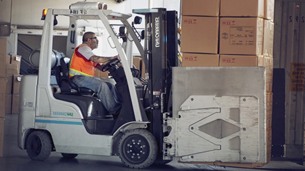 Side view of a worker in a forklift truck consolidating LCL cargo in boxes.