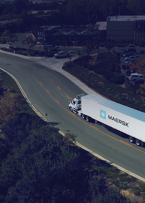 A Maersk shipping container truck on a highway
